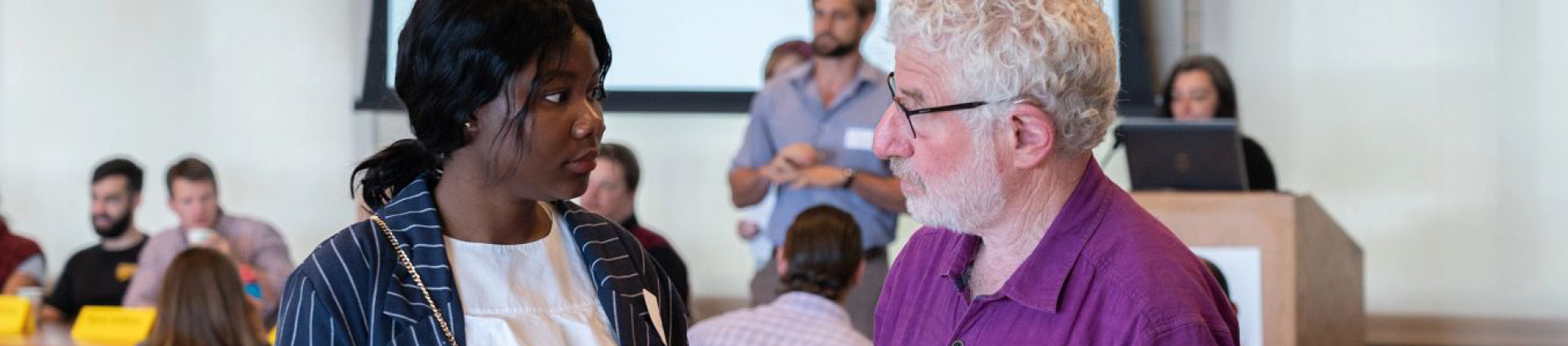 Two individuals speaking with one another in a large meeting room